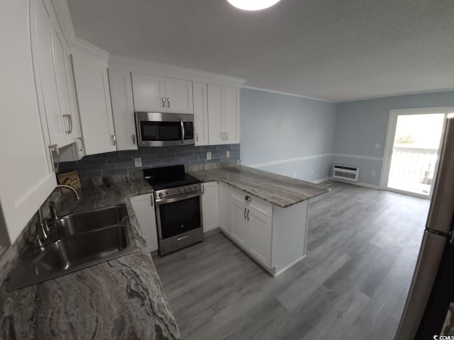 300 47th Ave S Unit 1F, North Myrtle Beach, SC 29582 - kitchen with stainless steel appliances, a sink, a peninsula, tasteful backsplash, and white cabinetry