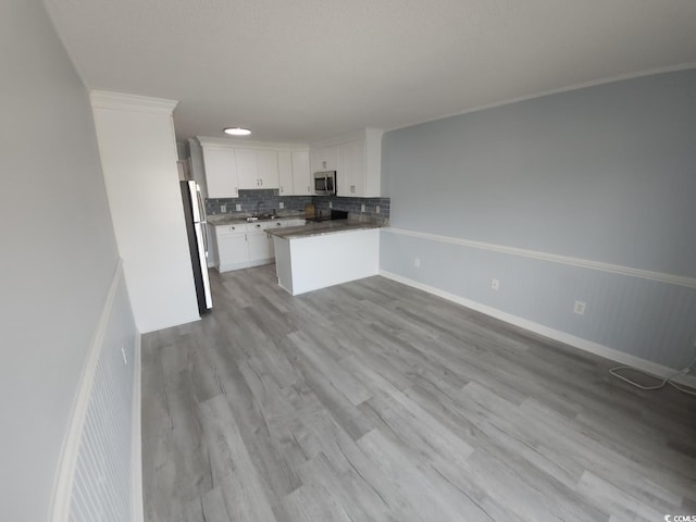 300 47th Ave S Unit 1F, North Myrtle Beach, SC 29582 - kitchen featuring stainless steel appliances, a peninsula, white cabinetry, backsplash, and open floor plan