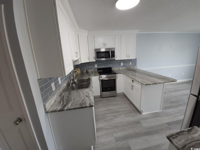 300 47th Ave S Unit 1F, North Myrtle Beach, SC 29582 - kitchen with appliances with stainless steel finishes, a sink, a peninsula, backsplash, and white cabinets