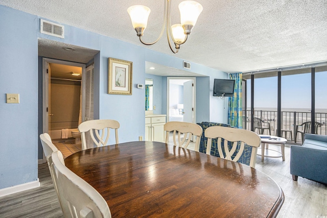 9400 Shore Dr Unit 124, Myrtle Beach, SC 29572 - dining space featuring wood finished floors, a textured ceiling, expansive windows, a chandelier, and baseboards