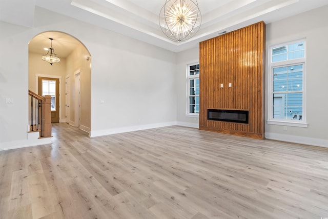 2205 Yellow Morel Way, Myrtle Beach, SC 29579 - unfurnished living room with a chandelier, a tray ceiling, arched walkways, and light wood-type flooring