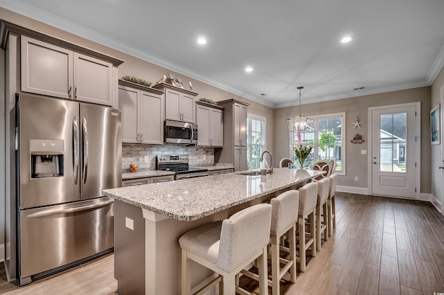 620 Lorenzo Dr Unit 620, North Myrtle Beach, SC 29582 - kitchen with stainless steel appliances, an island with sink, light stone counters, a breakfast bar area, and light wood-style floors