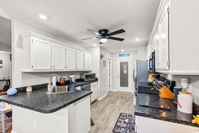 127 Coachman Ln, Surfside Beach, SC 29575 - kitchen with black range oven, a sink, white cabinetry, a peninsula, and a textured ceiling