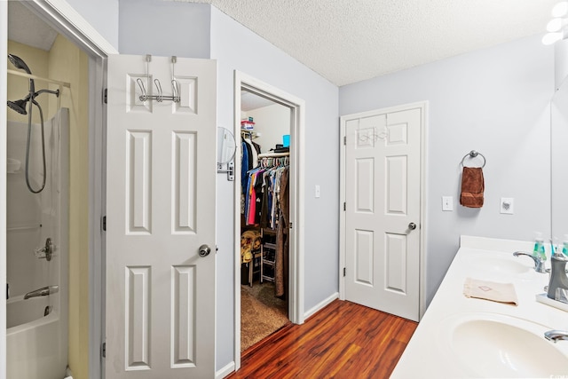 127 Coachman Ln, Surfside Beach, SC 29575 - full bathroom with wood finished floors, double vanity,  shower combination, a walk in closet, and a textured ceiling