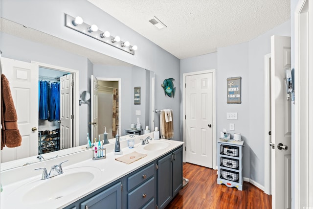 127 Coachman Ln, Surfside Beach, SC 29575 - bathroom featuring double vanity, wood finished floors, and a textured ceiling
