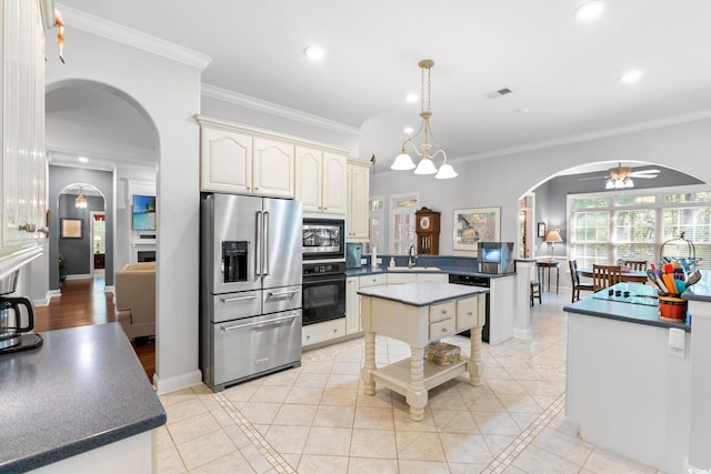 6572 Wellington Dr, Murrells Inlet, SC 29576 - kitchen featuring black appliances, arched walkways, cream cabinetry, a peninsula, and a ceiling fan