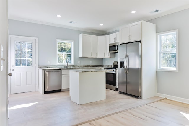 155 Mckenzie Cir, Pawleys Island, SC 29585 - kitchen with stainless steel appliances, ornamental molding, light wood-type flooring, a center island, and white cabinets