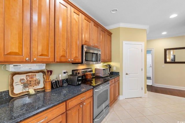 702 Compass Point Dr, North Myrtle Beach, SC 29582 - kitchen with appliances with stainless steel finishes, brown cabinets, ornamental molding, light tile patterned floors, and dark stone countertops