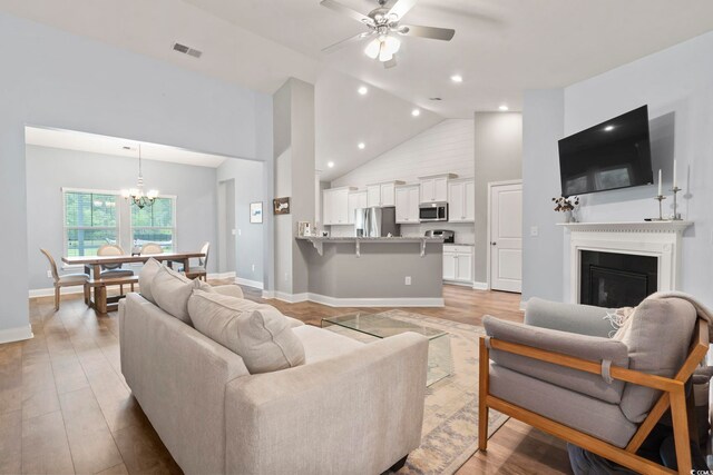 223 Southgate Ct, Pawleys Island, SC 29585 - living area with a chandelier, a ceiling fan, high vaulted ceiling, a glass covered fireplace, and light wood-type flooring