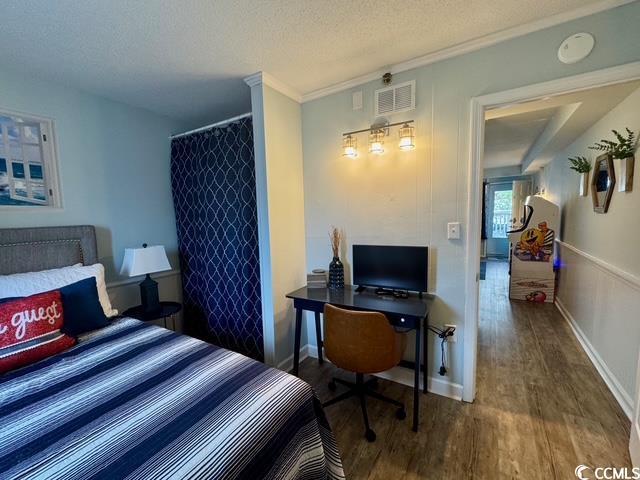 5409 N Ocean Blvd Unit 111, North Myrtle Beach, SC 29582 - bedroom with wood finished floors, an office area, a textured ceiling, baseboards, and ornamental molding