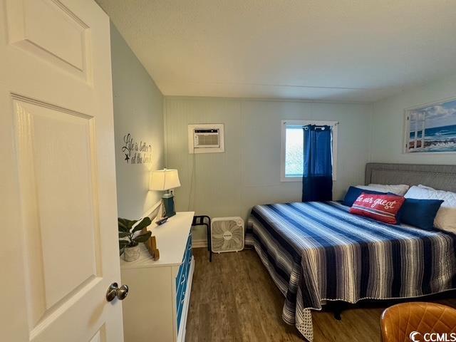 5409 N Ocean Blvd Unit 111, North Myrtle Beach, SC 29582 - bedroom featuring a wall mounted AC and dark wood-style floors