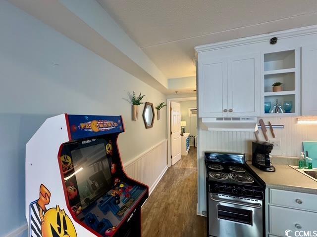 5409 N Ocean Blvd Unit 111, North Myrtle Beach, SC 29582 - kitchen with stainless steel gas range, ventilation hood, wainscoting, light countertops, and dark wood-type flooring
