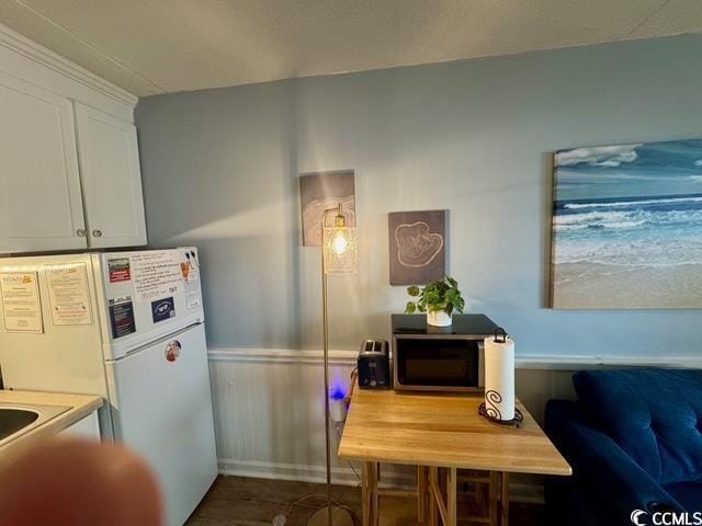 5409 N Ocean Blvd Unit 111, North Myrtle Beach, SC 29582 - kitchen featuring wainscoting, freestanding refrigerator, and white cabinets