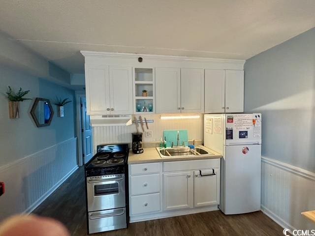 5409 N Ocean Blvd Unit 111, North Myrtle Beach, SC 29582 - kitchen with under cabinet range hood, electric stove, freestanding refrigerator, white cabinetry, and wainscoting