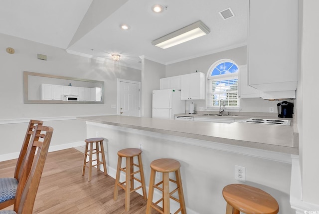 4811 Orchid Way Unit 301, Myrtle Beach, SC 29577 - kitchen featuring white appliances, a peninsula, a kitchen bar, light wood-style floors, and white cabinetry