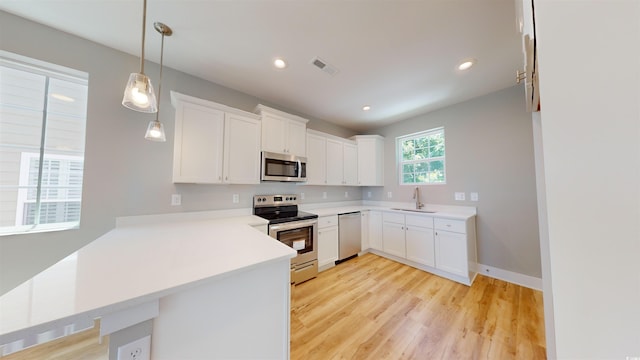 52 Fish Shack Aly, Murrells Inlet, SC 29576 - kitchen with stainless steel appliances, a peninsula, light wood-type flooring, light countertops, and white cabinets