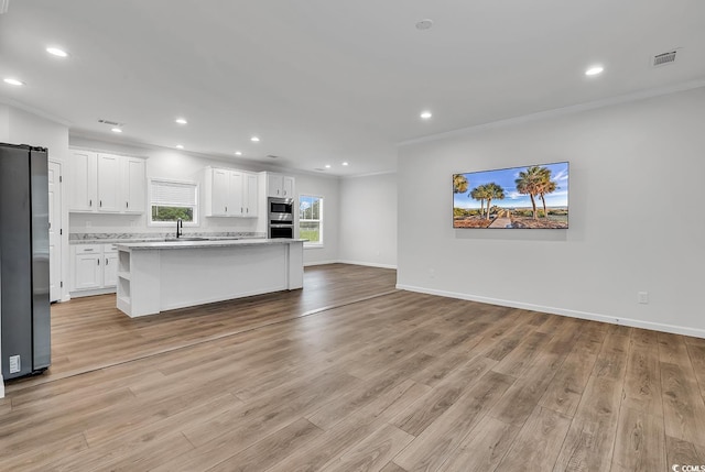1529 Bucksport Rd, Conway, SC 29527 - kitchen with stainless steel appliances, ornamental molding, open floor plan, white cabinets, and light wood-style floors