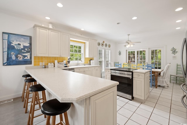 214 Sea Island Dr, Georgetown, SC 29440 - kitchen with electric range, light countertops, a breakfast bar area, backsplash, and a ceiling fan
