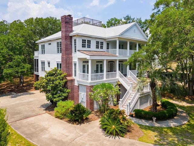 214 Sea Island Dr, Georgetown, SC 29440 - view of front facade featuring covered porch, a standing seam roof, stairway, a balcony, and a chimney