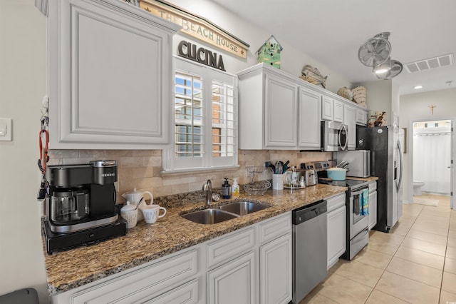 603 Wave Rider Ln Unit 603, North Myrtle Beach, SC 29582 - kitchen featuring stainless steel appliances, a sink, decorative backsplash, light tile patterned flooring, and dark stone counters