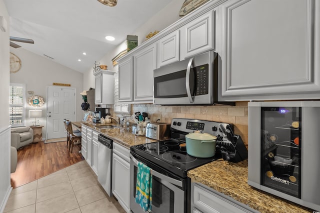 603 Wave Rider Ln Unit 603, North Myrtle Beach, SC 29582 - kitchen with stainless steel appliances, backsplash, lofted ceiling, light tile patterned flooring, and light stone countertops