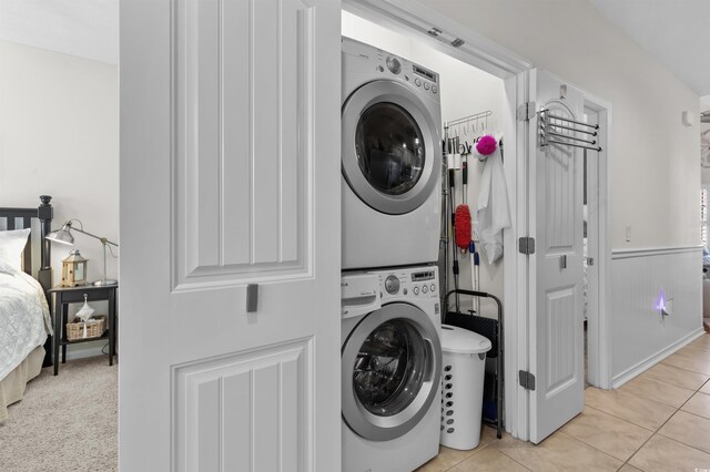 603 Wave Rider Ln Unit 603, North Myrtle Beach, SC 29582 - laundry room featuring stacked washing machine and dryer, light tile patterned floors, and wainscoting