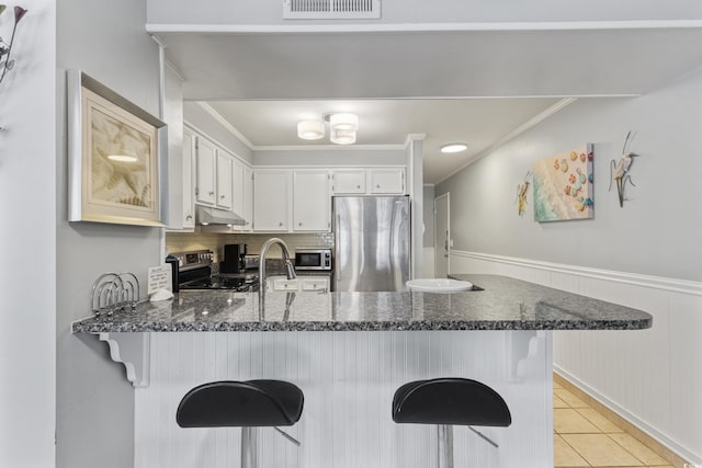 202 N Ocean Blvd Unit 109, North Myrtle Beach, SC 29582 - kitchen featuring appliances with stainless steel finishes, a peninsula, ornamental molding, under cabinet range hood, and light tile patterned floors