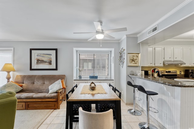 202 N Ocean Blvd Unit 109, North Myrtle Beach, SC 29582 - kitchen with under cabinet range hood, light tile patterned flooring, crown molding, dark stone countertops, and ceiling fan