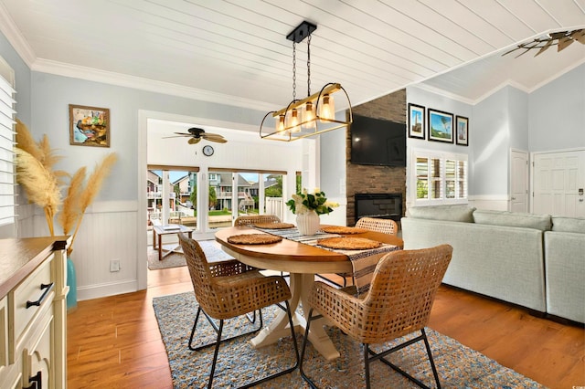 39 Newport St, Ocean Isle Beach, NC 28469 - dining space featuring a ceiling fan, crown molding, a large fireplace, light wood-style floors, and wainscoting