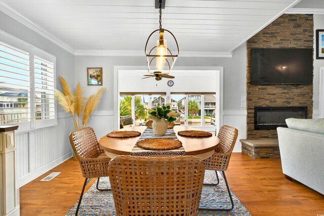 39 Newport St, Ocean Isle Beach, NC 28469 - dining room with wood finished floors, a stone fireplace, a wainscoted wall, and crown molding