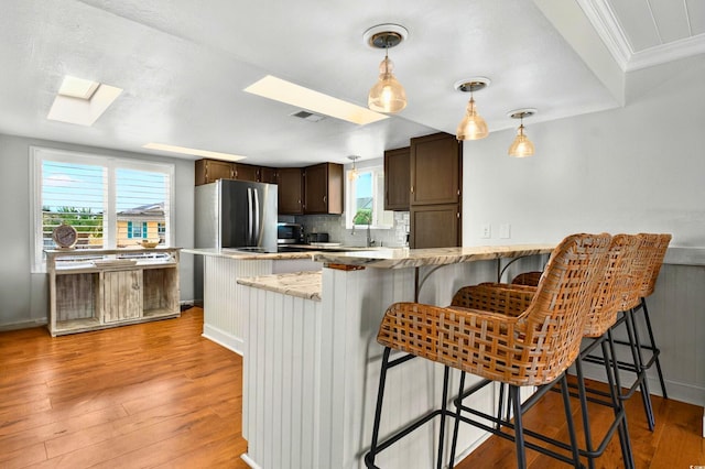 39 Newport St, Ocean Isle Beach, NC 28469 - kitchen featuring freestanding refrigerator, a skylight, dark brown cabinets, light wood-type flooring, and ornamental molding