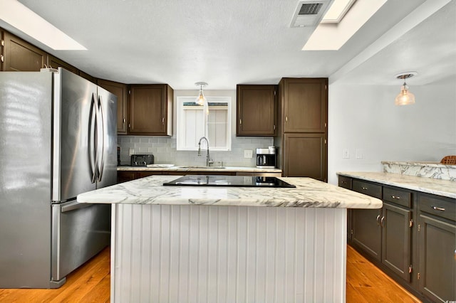 39 Newport St, Ocean Isle Beach, NC 28469 - kitchen featuring freestanding refrigerator, a sink, black electric stovetop, tasteful backsplash, and light wood finished floors