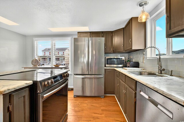 39 Newport St, Ocean Isle Beach, NC 28469 - kitchen featuring stainless steel appliances, a sink, a skylight, tasteful backsplash, and light wood finished floors