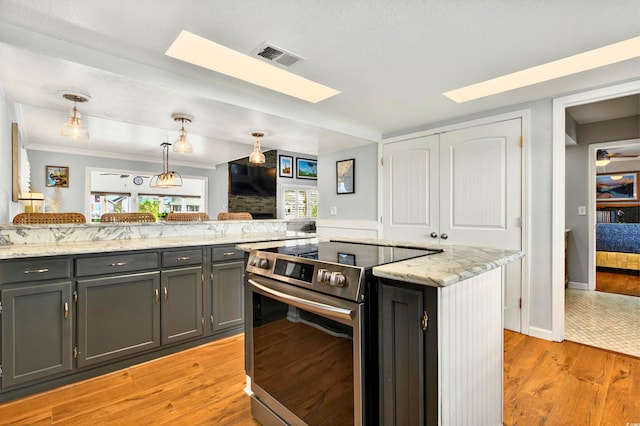 39 Newport St, Ocean Isle Beach, NC 28469 - kitchen with stainless steel electric range oven, a skylight, decorative light fixtures, light wood-style flooring, and light stone counters