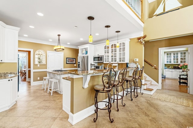 1119 Links Rd, Myrtle Beach, SC 29575 - kitchen featuring appliances with stainless steel finishes, white cabinetry, a kitchen bar, light stone countertops, and a peninsula