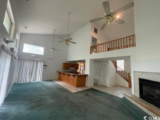 2862 Loblolly Ave, Little River, SC 29566 - unfurnished living room featuring high vaulted ceiling, a ceiling fan, a tile fireplace, light carpet, and stairway