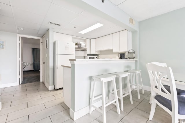 201 74th Ave N Unit 2243/2244, Myrtle Beach, SC 29572 - kitchen with freestanding refrigerator, a breakfast bar area, a peninsula, white cabinets, and light countertops