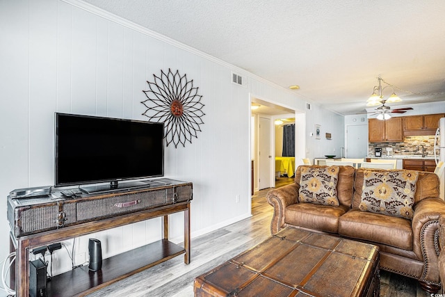 6000 N Ocean Blvd Unit 329, North Myrtle Beach, SC 29582 - living room featuring ornamental molding, light wood finished floors, a ceiling fan, a textured ceiling, and baseboards
