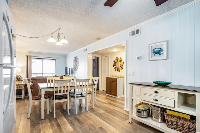 6000 N Ocean Blvd Unit 329, North Myrtle Beach, SC 29582 - dining space featuring ornamental molding, a textured ceiling, a chandelier, a ceiling fan, and light wood finished floors