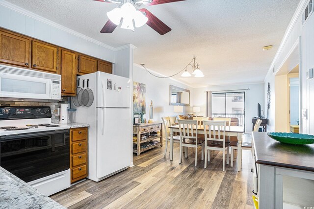 6000 N Ocean Blvd Unit 329, North Myrtle Beach, SC 29582 - kitchen with white appliances, brown cabinets, ornamental molding, a textured ceiling, and light wood-style flooring