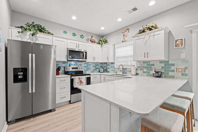 503 20th Ave N Unit 55B, North Myrtle Beach, SC 29582 - kitchen featuring appliances with stainless steel finishes, a sink, a peninsula, white cabinetry, and light stone countertops