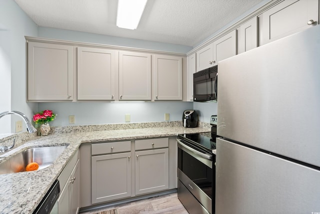 435 Ocean Creek Dr Unit 2722, Myrtle Beach, SC 29572 - kitchen featuring appliances with stainless steel finishes, a sink, light wood-type flooring, a textured ceiling, and light stone countertops