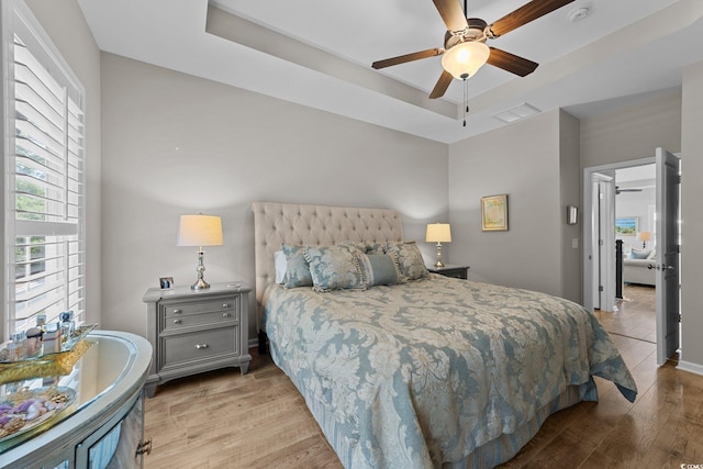 281 Lumbee Cir, Pawleys Island, SC 29585 - bedroom featuring a tray ceiling, multiple windows, wood finished floors, and a ceiling fan