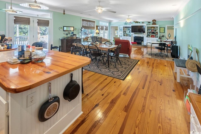 3926 Flagg St, Murrells Inlet, SC 29576 - dining room with ceiling fan, a fireplace, light wood-type flooring, crown molding, and healthy amount of natural light