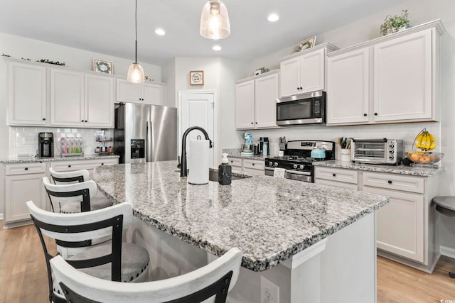4927 Sandlewood Dr, Myrtle Beach, SC 29579 - kitchen featuring stainless steel appliances, backsplash, a kitchen breakfast bar, a center island with sink, and white cabinets