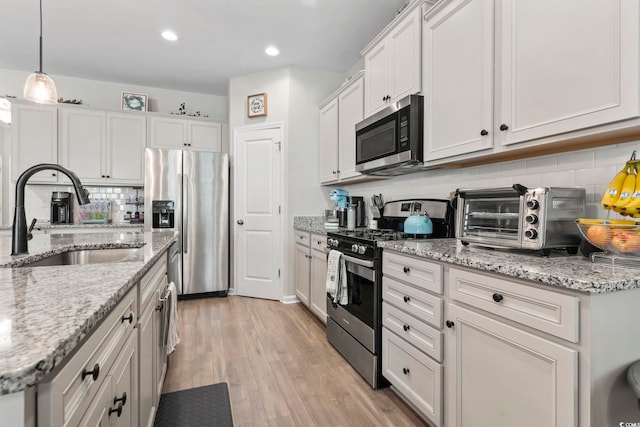 4927 Sandlewood Dr, Myrtle Beach, SC 29579 - kitchen featuring appliances with stainless steel finishes, a sink, tasteful backsplash, light wood-type flooring, and hanging light fixtures