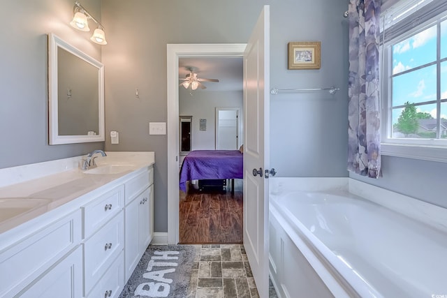 548 Fox Chase Dr, Conway, SC 29527 - bathroom featuring a garden tub, double vanity, ensuite bath, ceiling fan, and baseboards