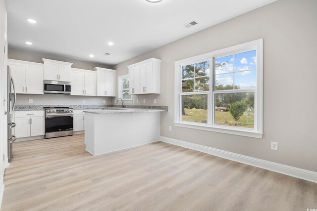 1900 Blue Bird Rd, Loris, SC 29569 - kitchen featuring stainless steel appliances, light wood-style flooring, light stone counters, a peninsula, and white cabinetry