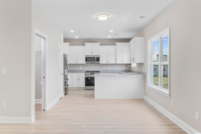 1900 Blue Bird Rd, Loris, SC 29569 - kitchen featuring appliances with stainless steel finishes, light wood finished floors, a peninsula, white cabinetry, and recessed lighting