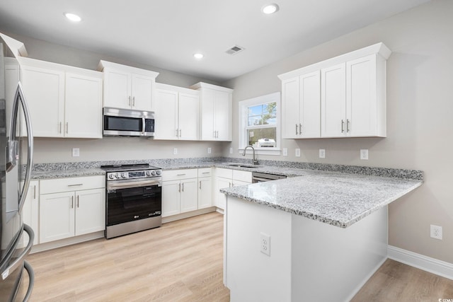 1900 Blue Bird Rd, Loris, SC 29569 - kitchen featuring stainless steel appliances, a peninsula, light stone counters, white cabinets, and light wood-style flooring